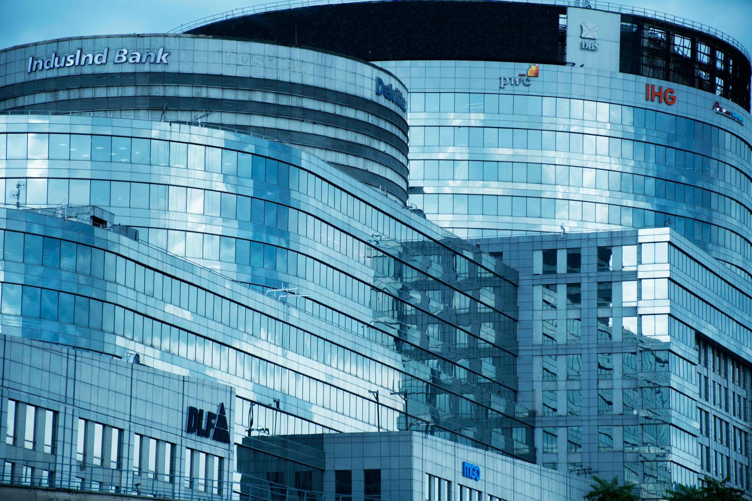 A contemporary glass skyscraper showcasing sleek architecture and corporate logos in an urban setting.